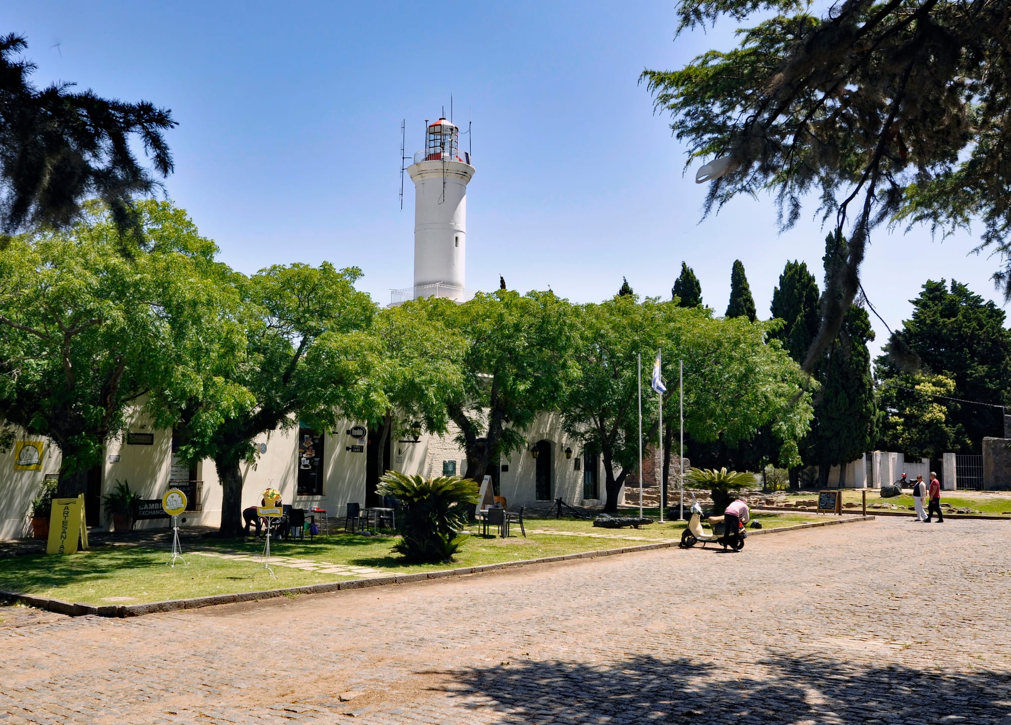 Colonial-era buildings and a lighthouse along a cobblestone street