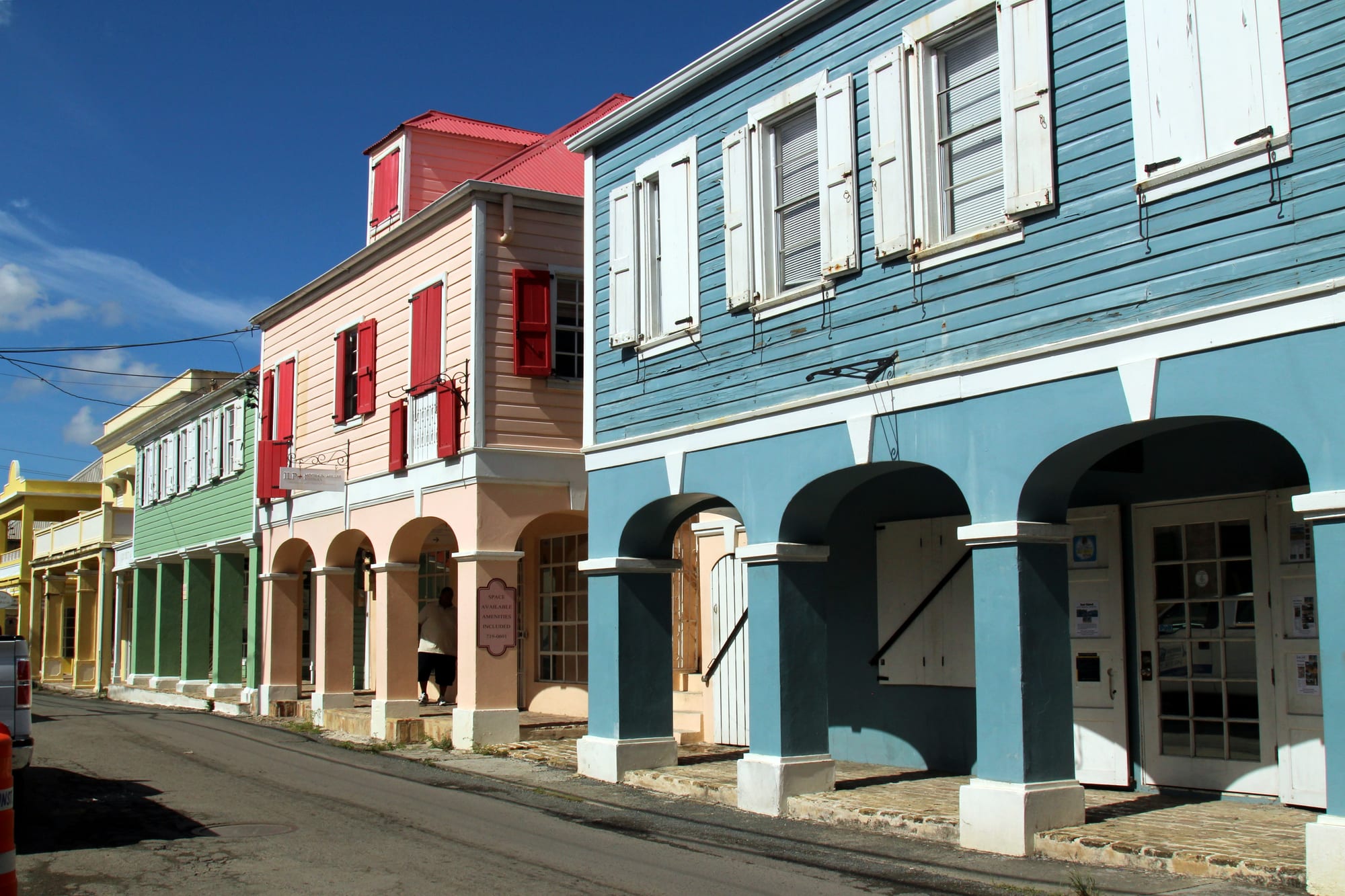 Brightly painted colonial buildings with arched arcades lining a street
