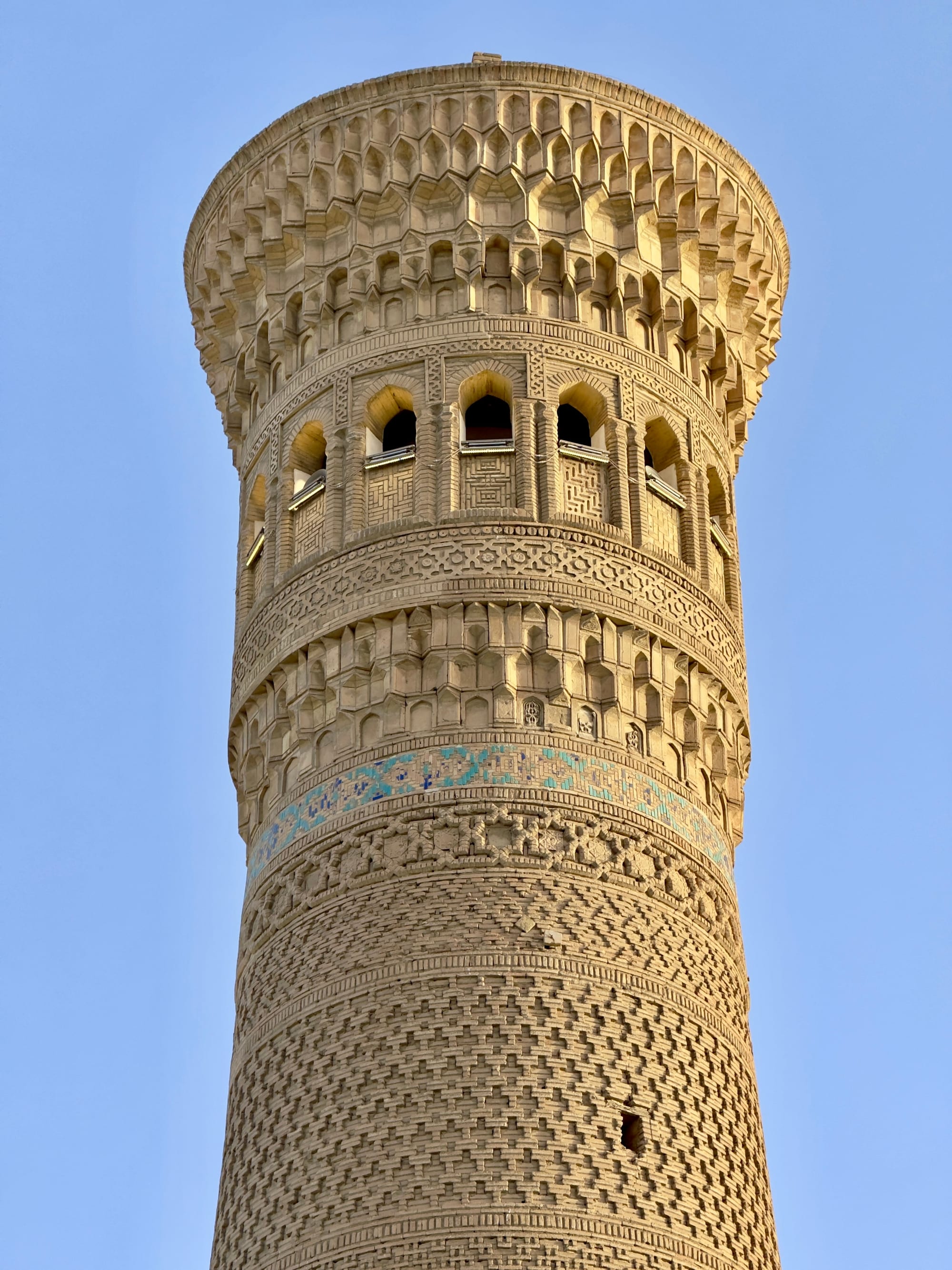 A tall ornately patterned minaret rising above a historic city
