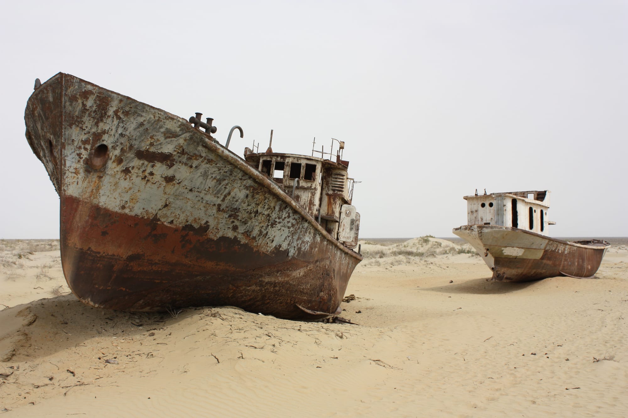 Rusting fishing boats stranded on cracked dry ground where the Aral Sea once was, near Moynaq