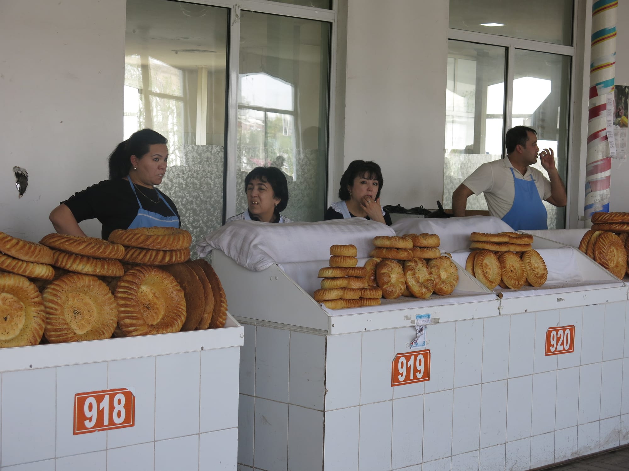 Vendors standing behind stalls piled with round flatbreads at a covered bazaar