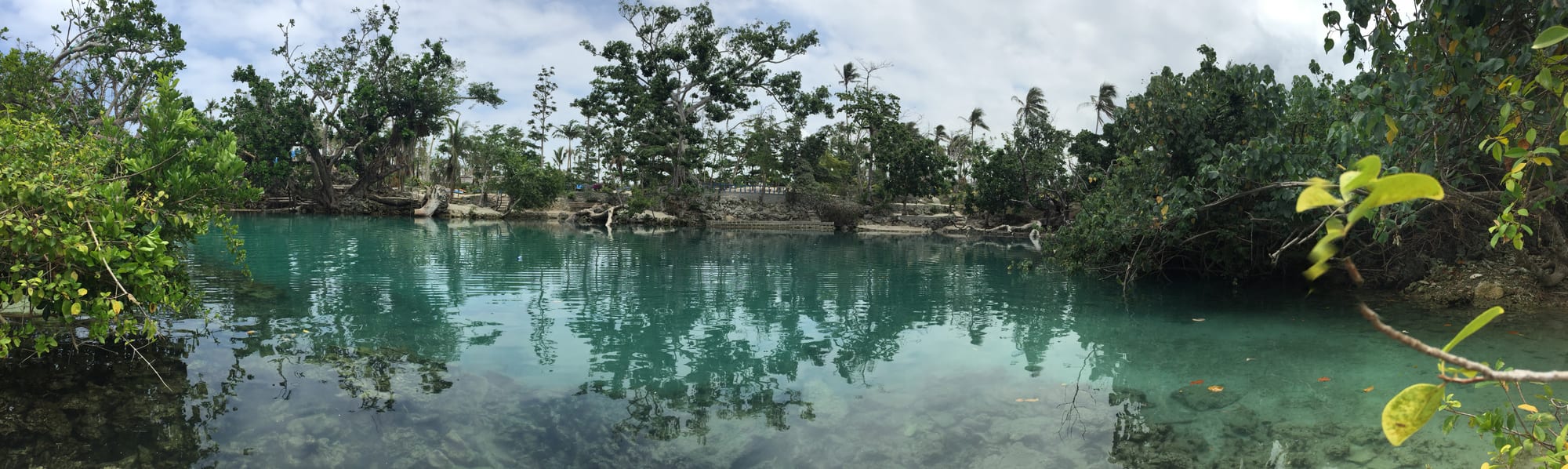 A vividly blue freshwater lagoon surrounded by tropical vegetation