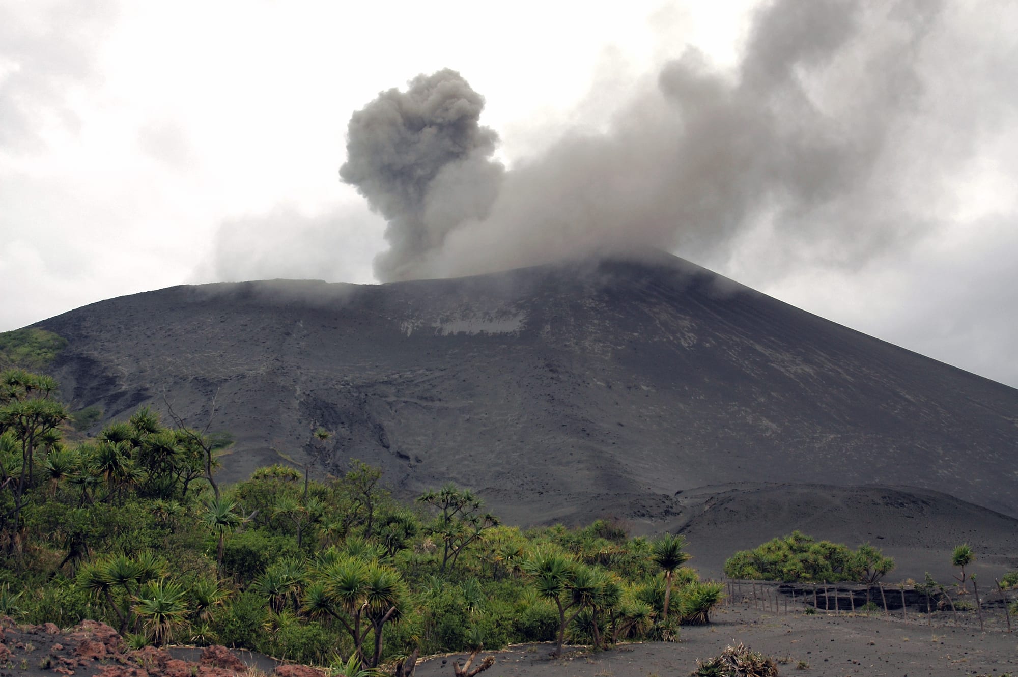 A volcano erupting with glowing lava and ash at night