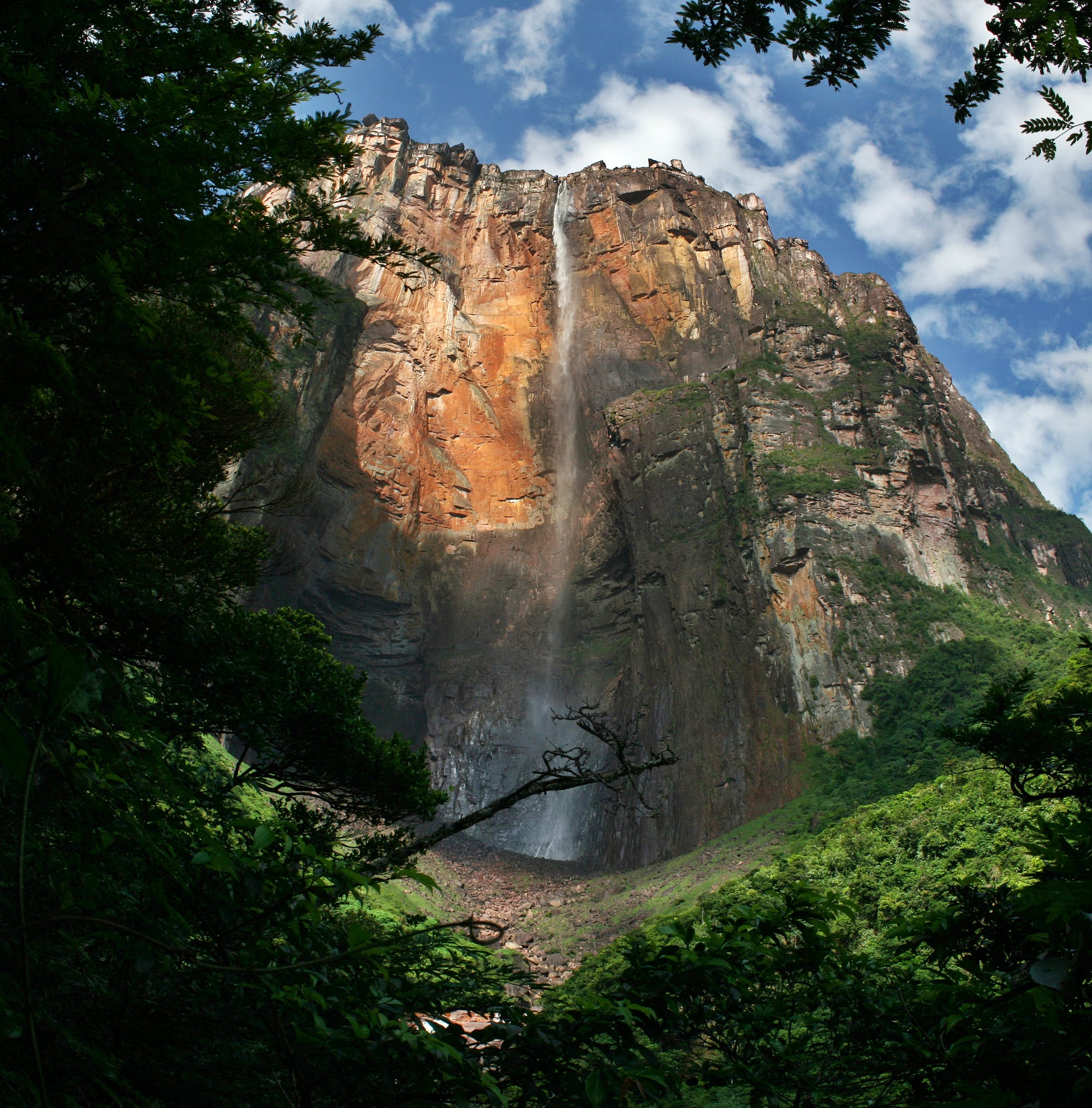 A tall thin waterfall descending from a flat-topped mountain cliff
