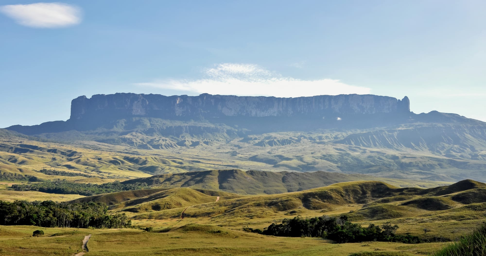A vast, sheer-walled tabletop mountain rising above the clouds