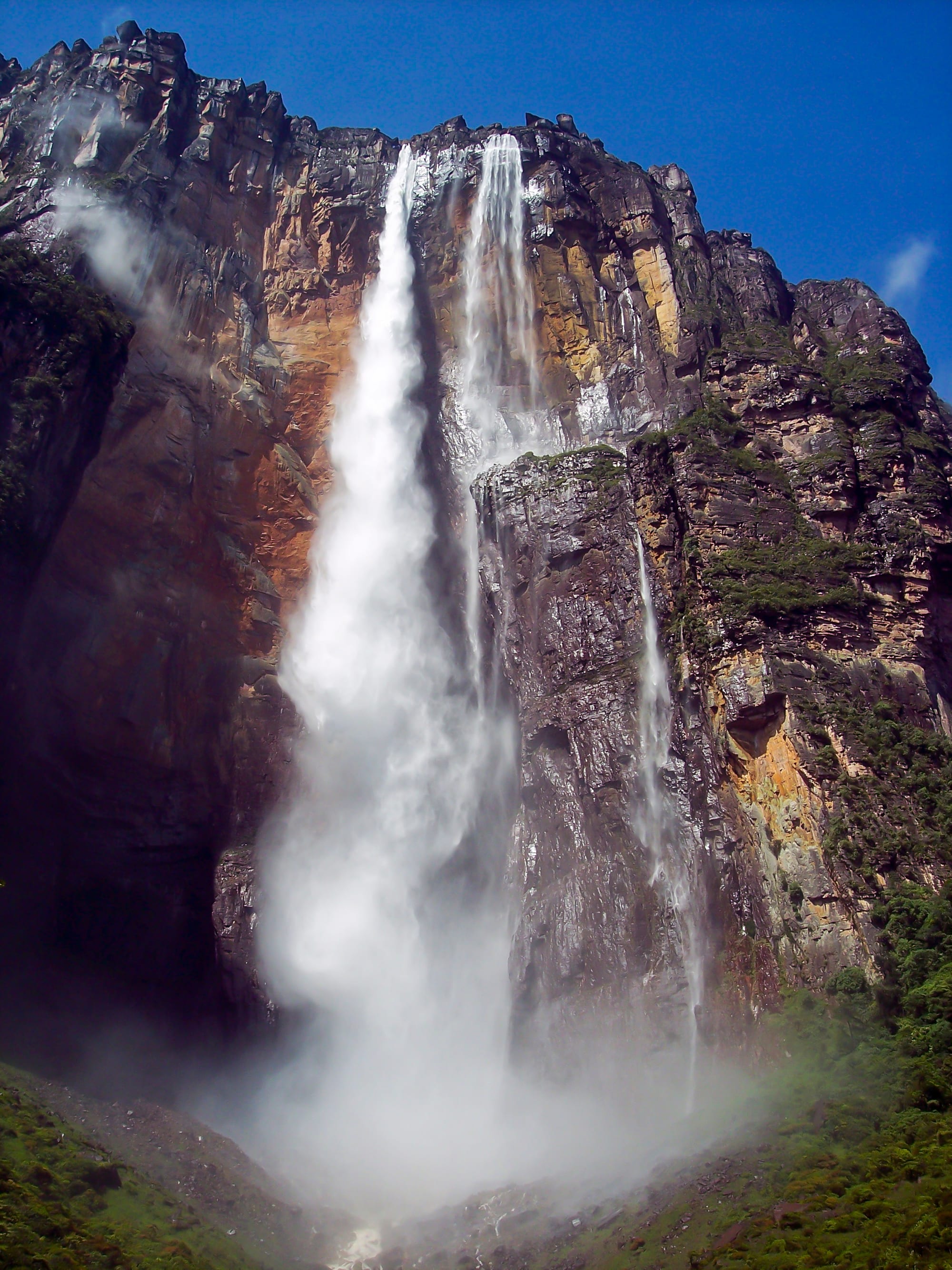 A massive waterfall plunging from a high tabletop cliff into dense rainforest