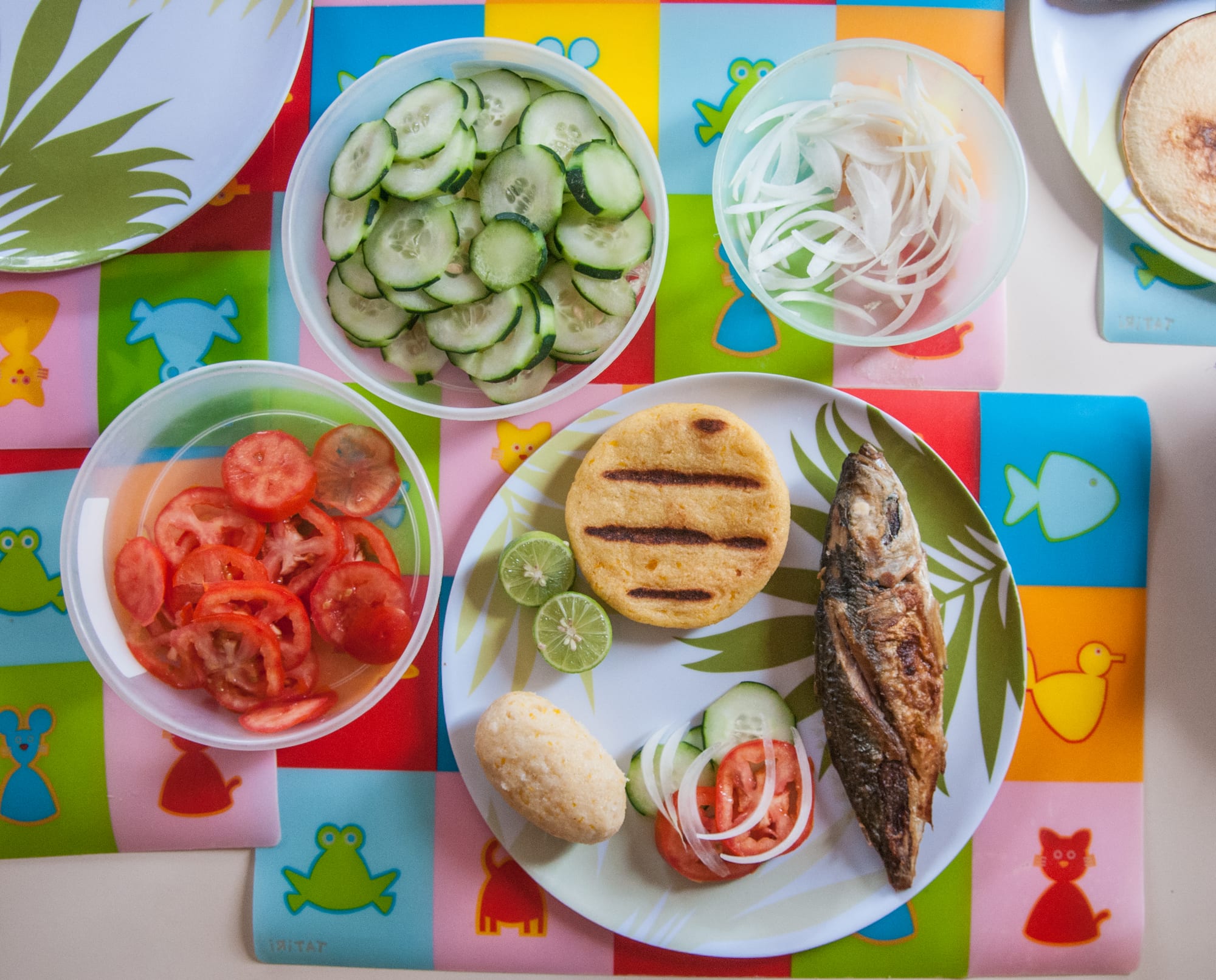 A grilled arepa served with fried fish and salad