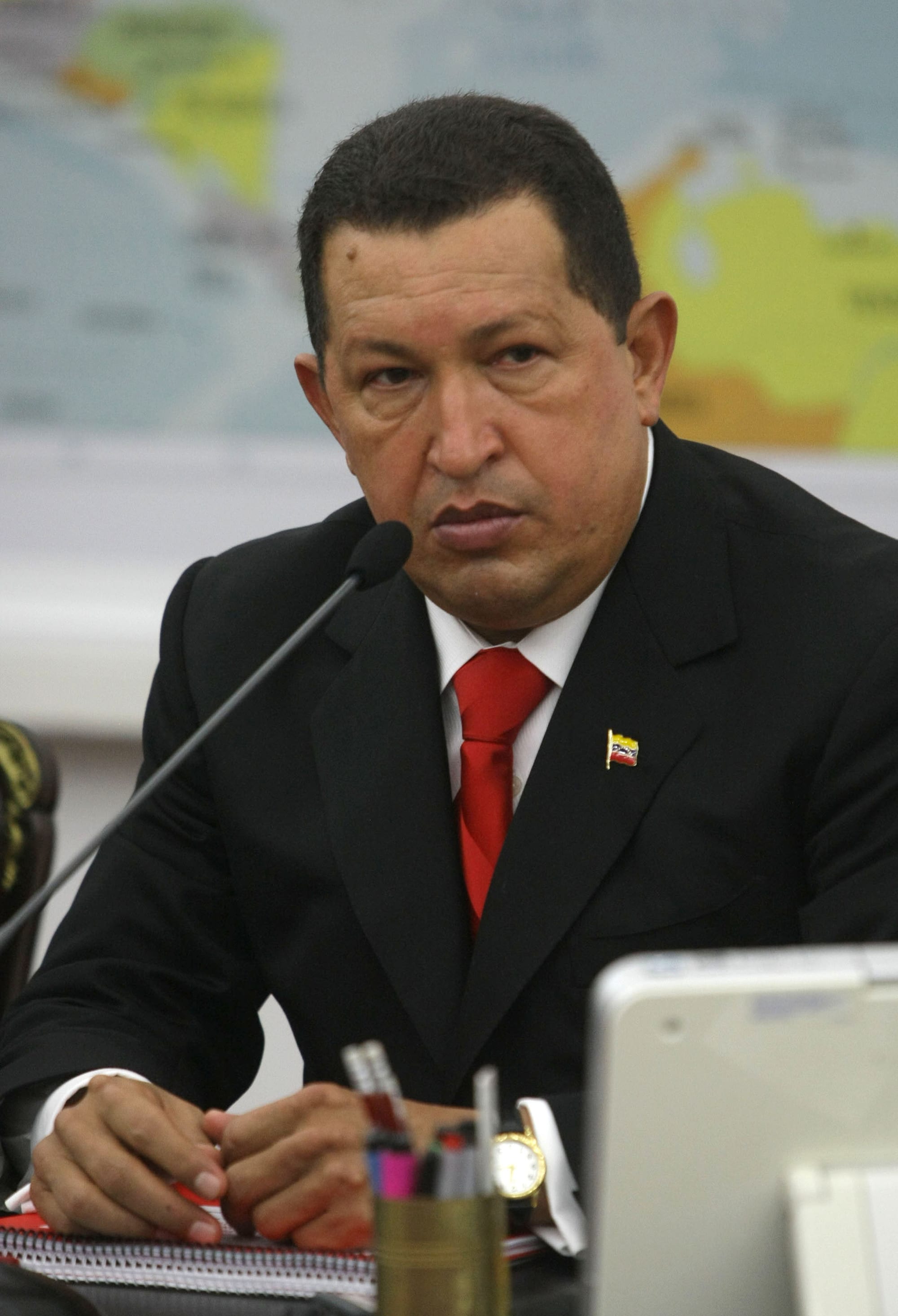 Hugo Chávez in a dark suit and red tie, gesturing while speaking, 2010
