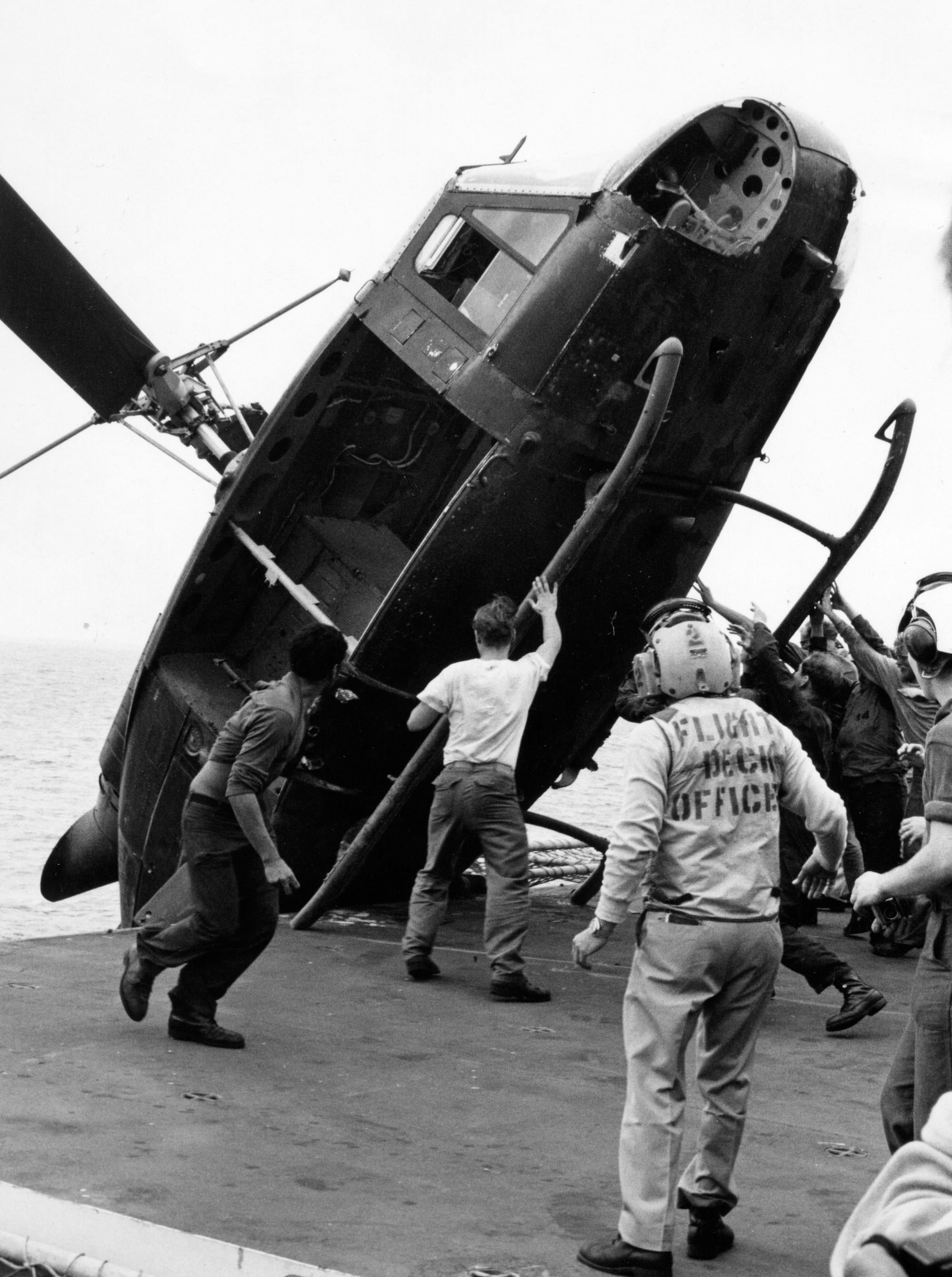 Sailors pushing a South Vietnamese helicopter off the deck of a US aircraft carrier to make room for more evacuees, 1975