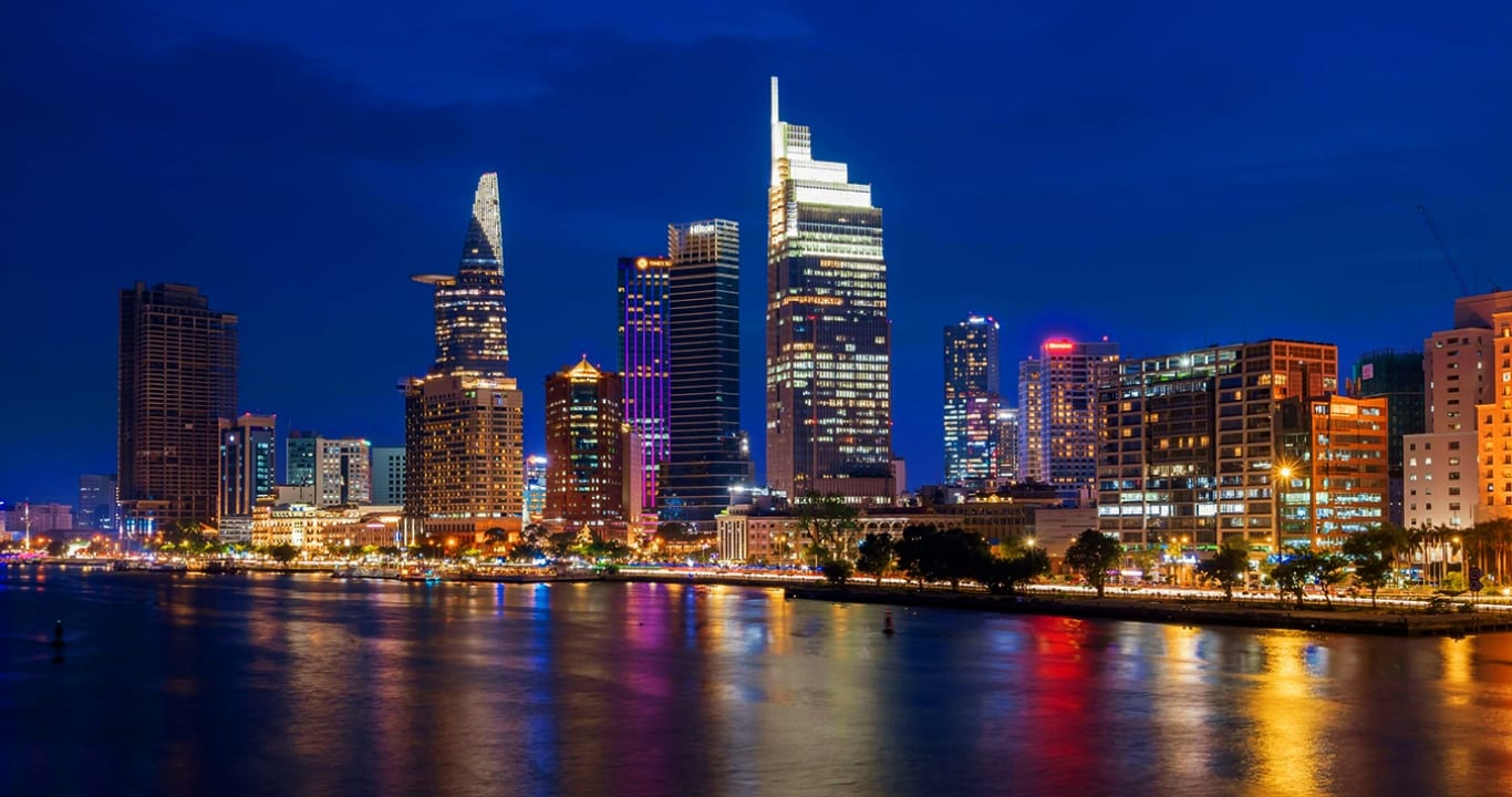 A modern city skyline illuminated at night along a river