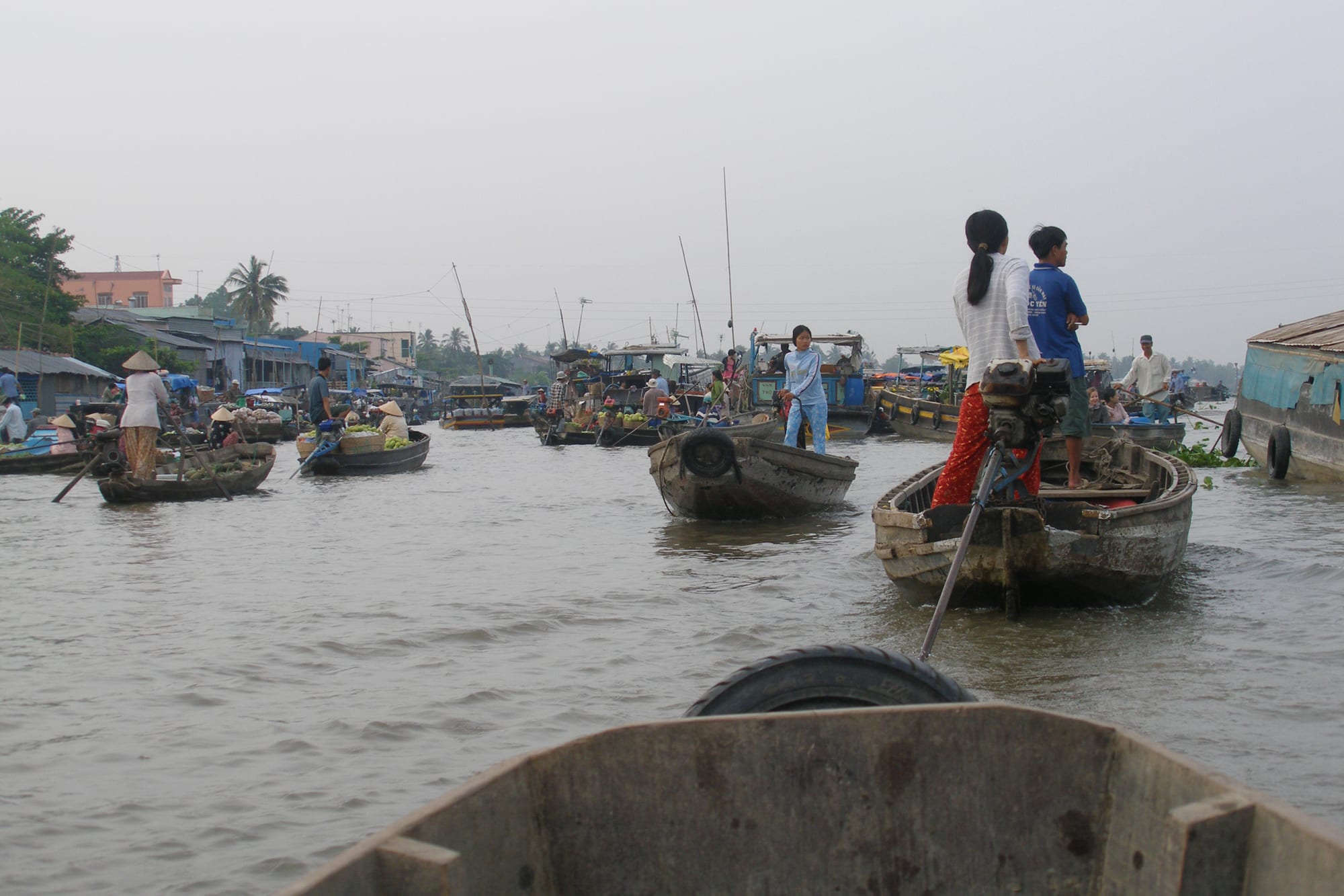 Wooden boats loaded with produce crowding a river at a floating market