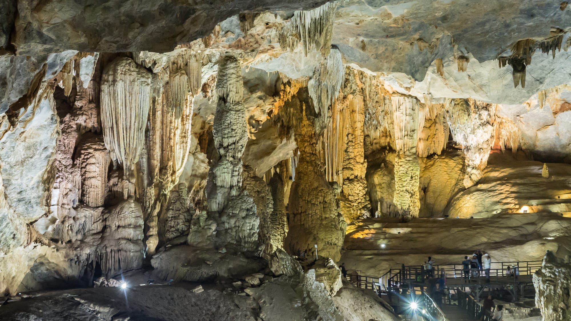 Massive stalactites hanging in an illuminated cave chamber