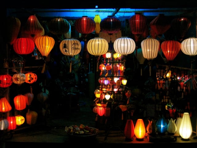 Colourful silk lanterns illuminated along a riverside street at night