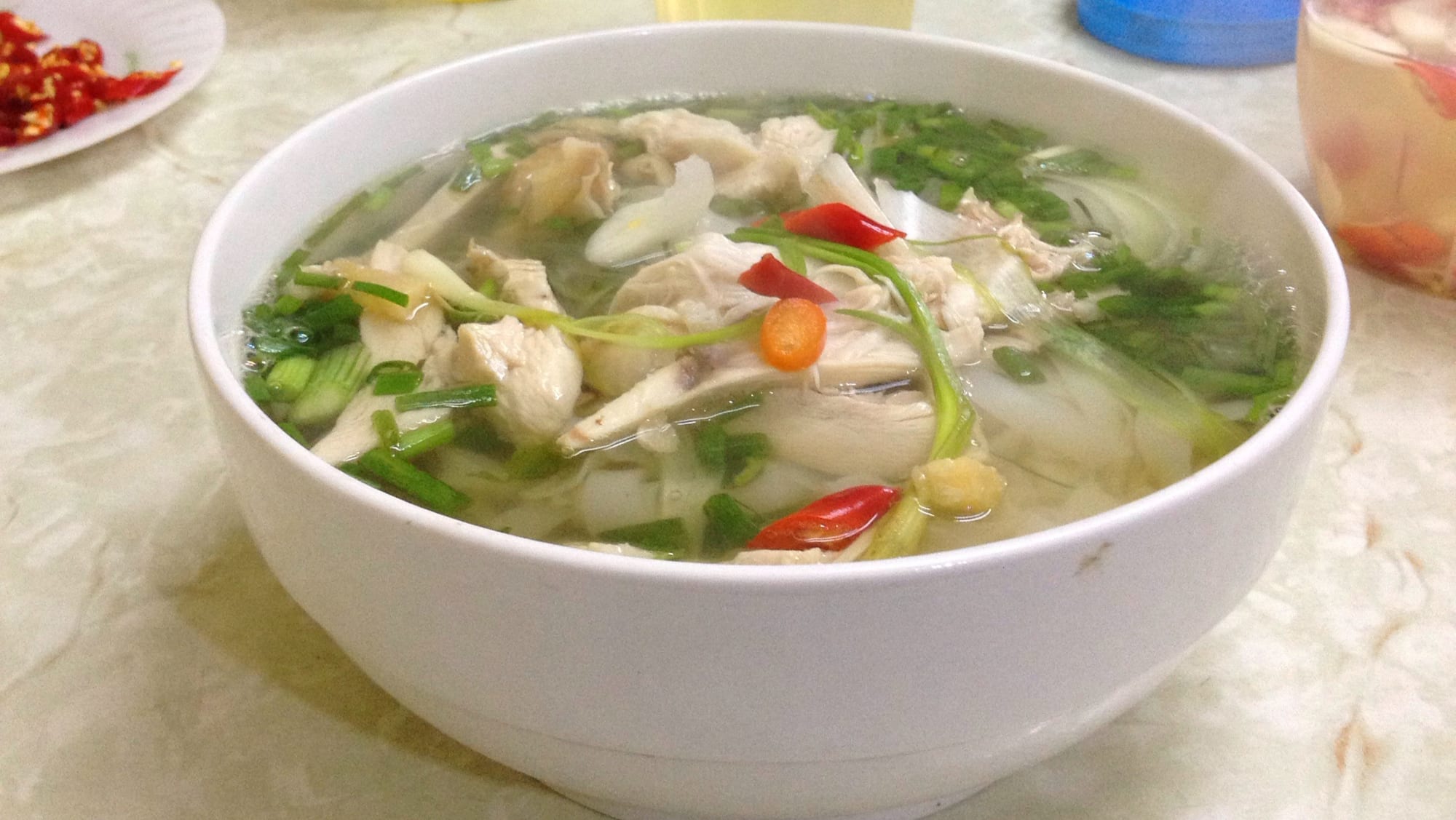 A bowl of noodle soup with herbs and chicken