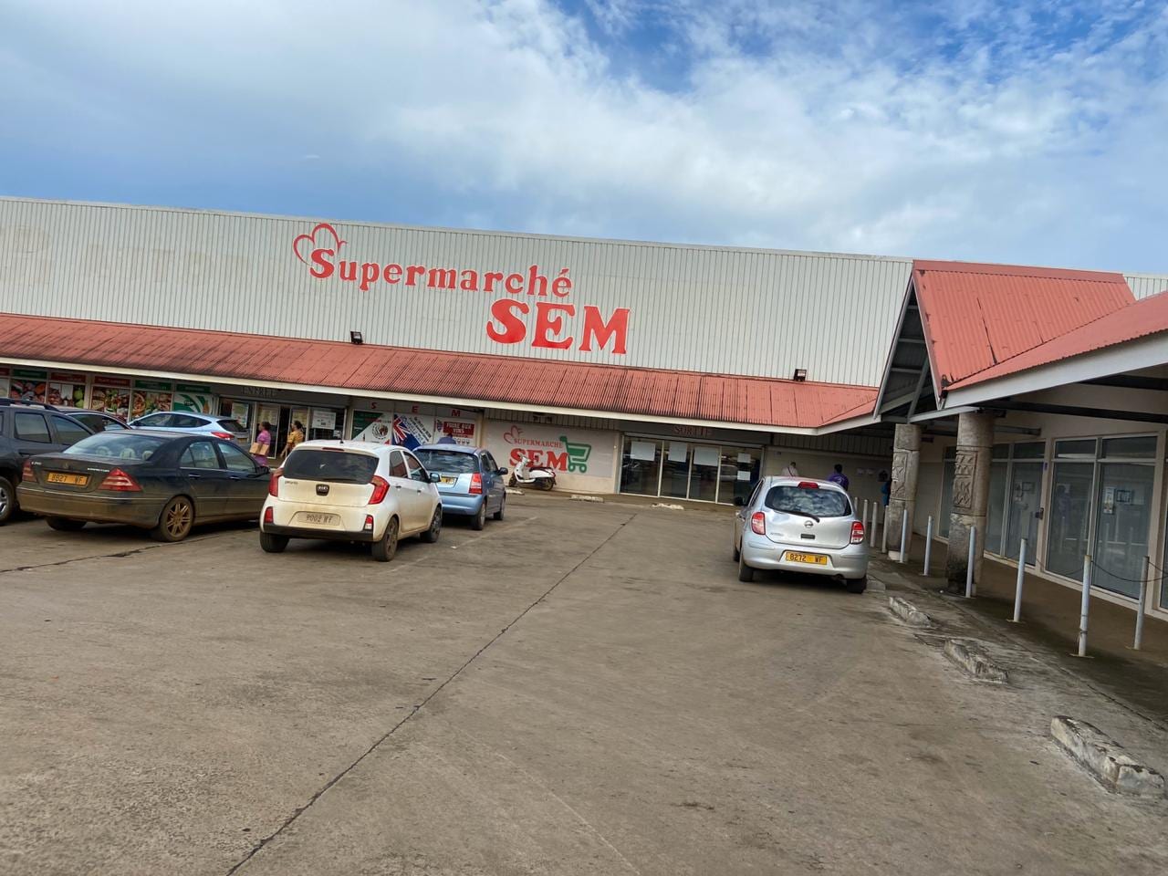 A supermarket building in Mata-Utu with a red roof and a sign reading Supermarché SEM, cars parked outside