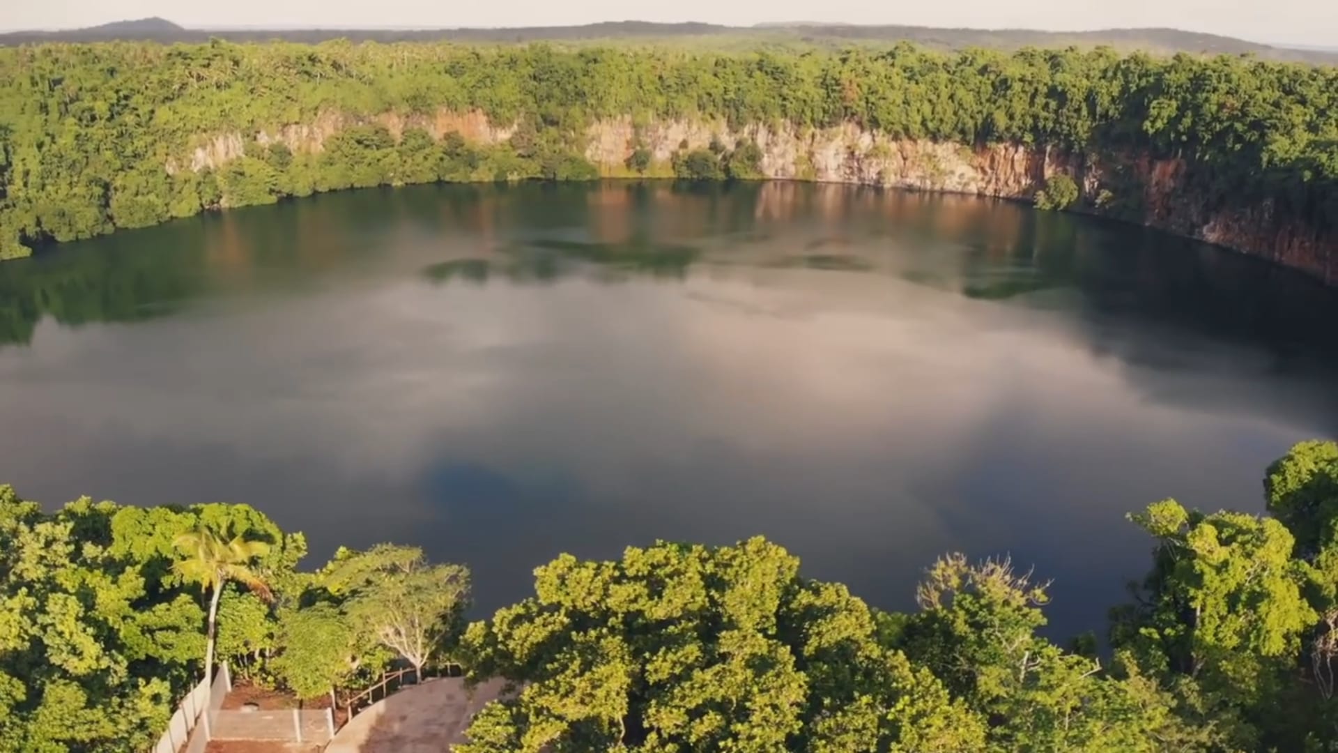A perfectly round volcanic crater lake surrounded by dense forest