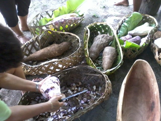 Women preparing root vegetables in woven baskets for an earth oven