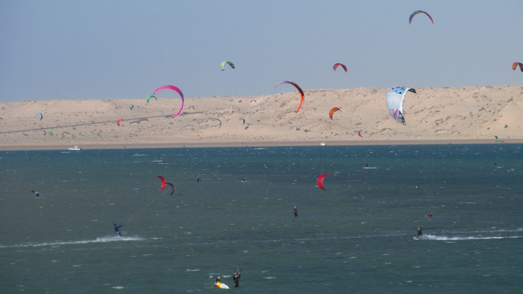 A kitesurfer riding waves in a calm coastal lagoon