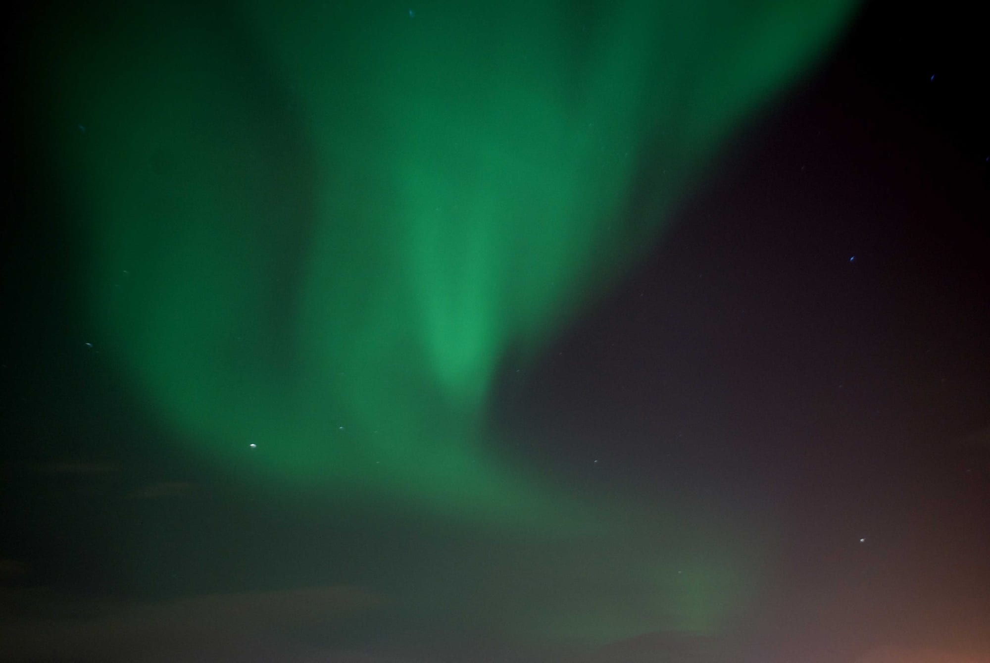 A broad, soft curtain of green light spreading across a dark starry sky