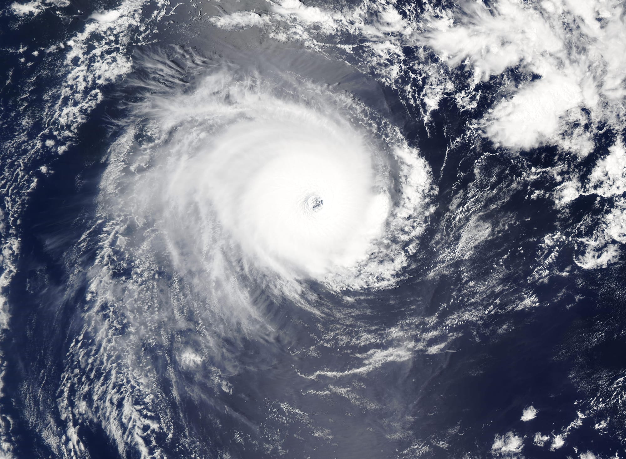 A tight white spiral of cloud with a small clear eye at its centre, over dark blue ocean