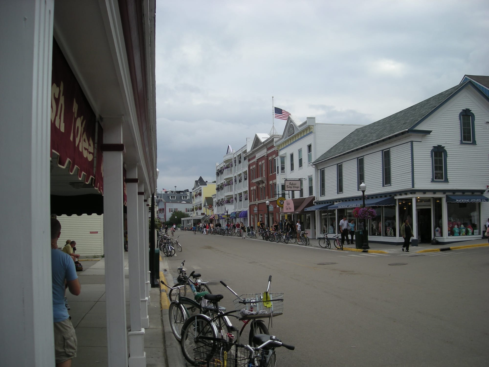 A wide street lined with white and red clapboard shops, with dozens of bicycles parked along both kerbs and pedestrians walking in the roadway