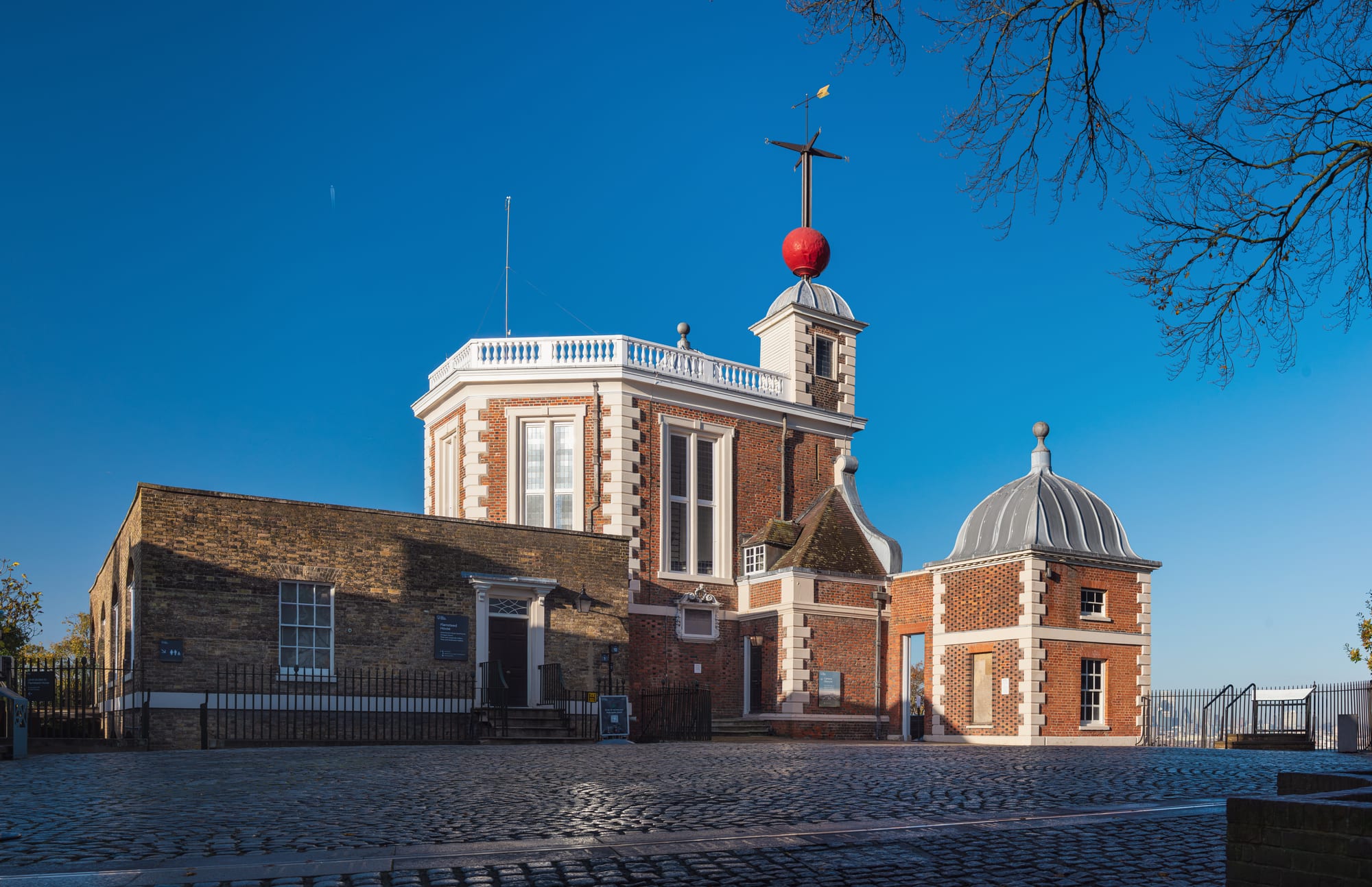A red-brick observatory building with a white balustrade and a large red ball on a mast above its turret