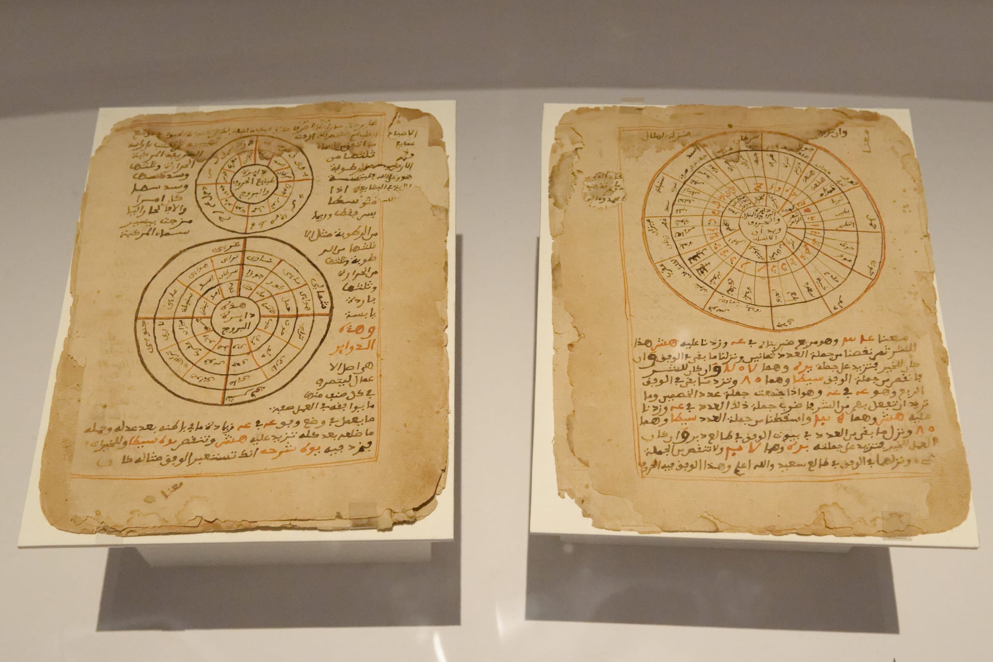 Two yellowed manuscript pages in Arabic script, each with circular diagrams drawn in brown and red ink