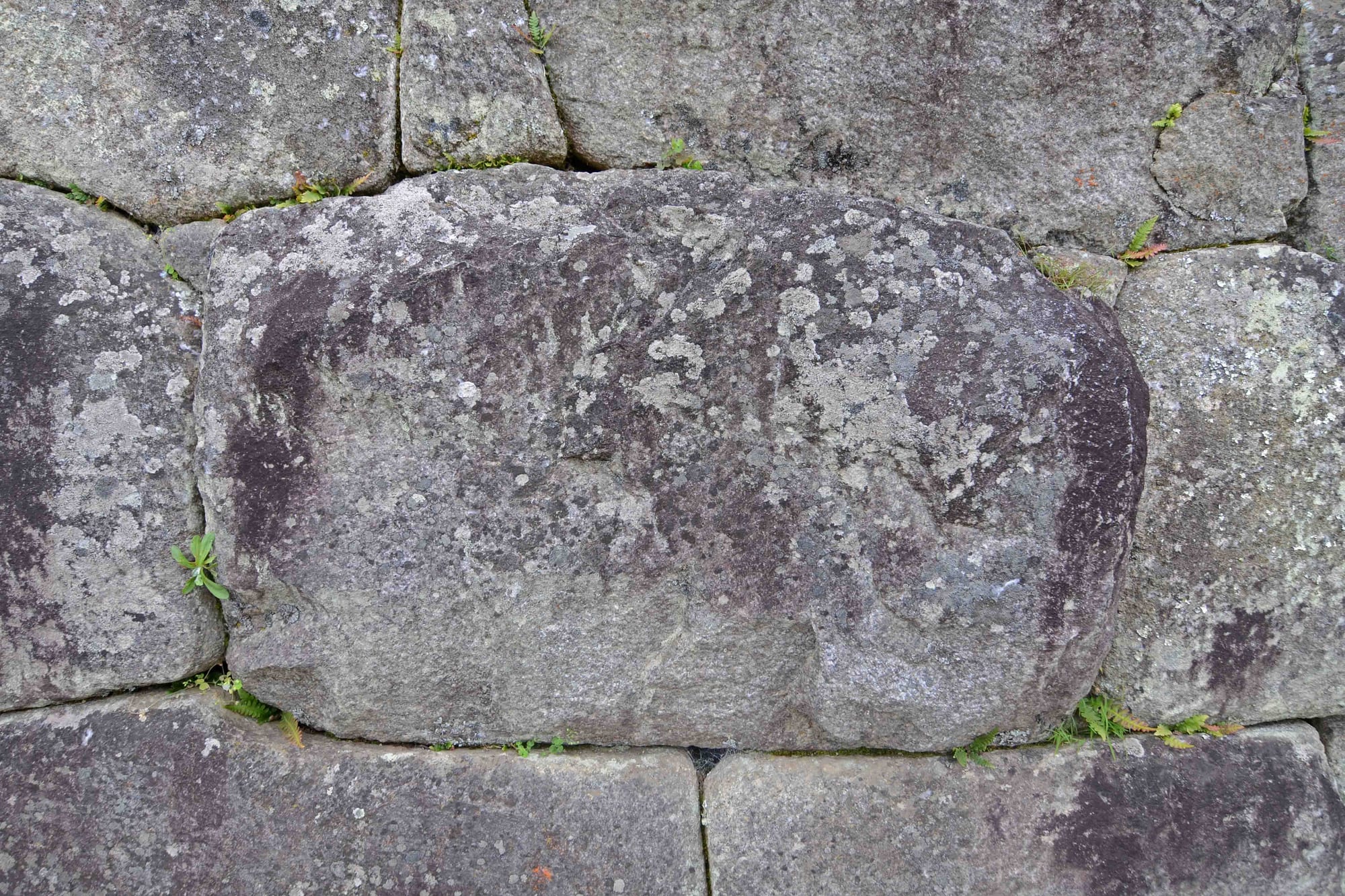 Close view of large grey granite blocks with rounded edges fitted tightly together without mortar