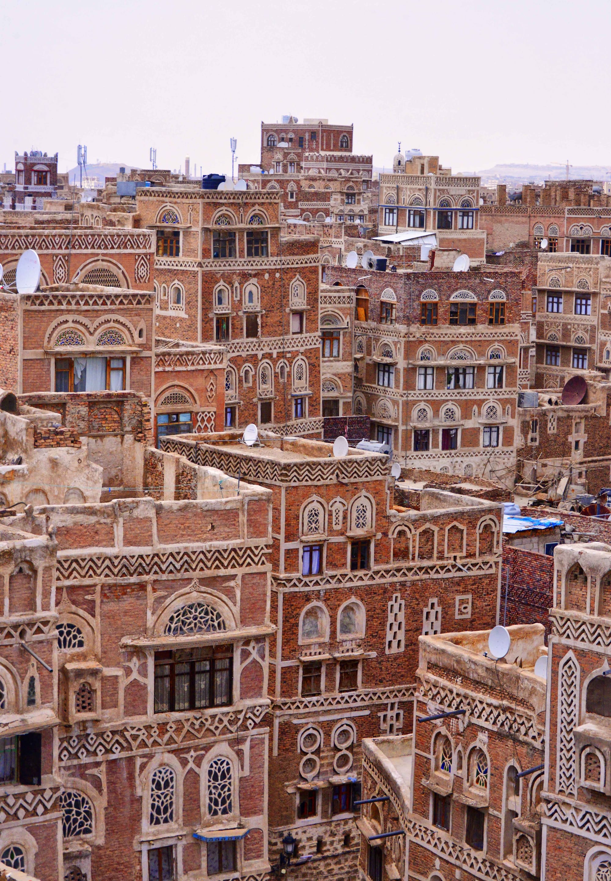 Tall mud-brick tower houses decorated with white geometric patterns along a street