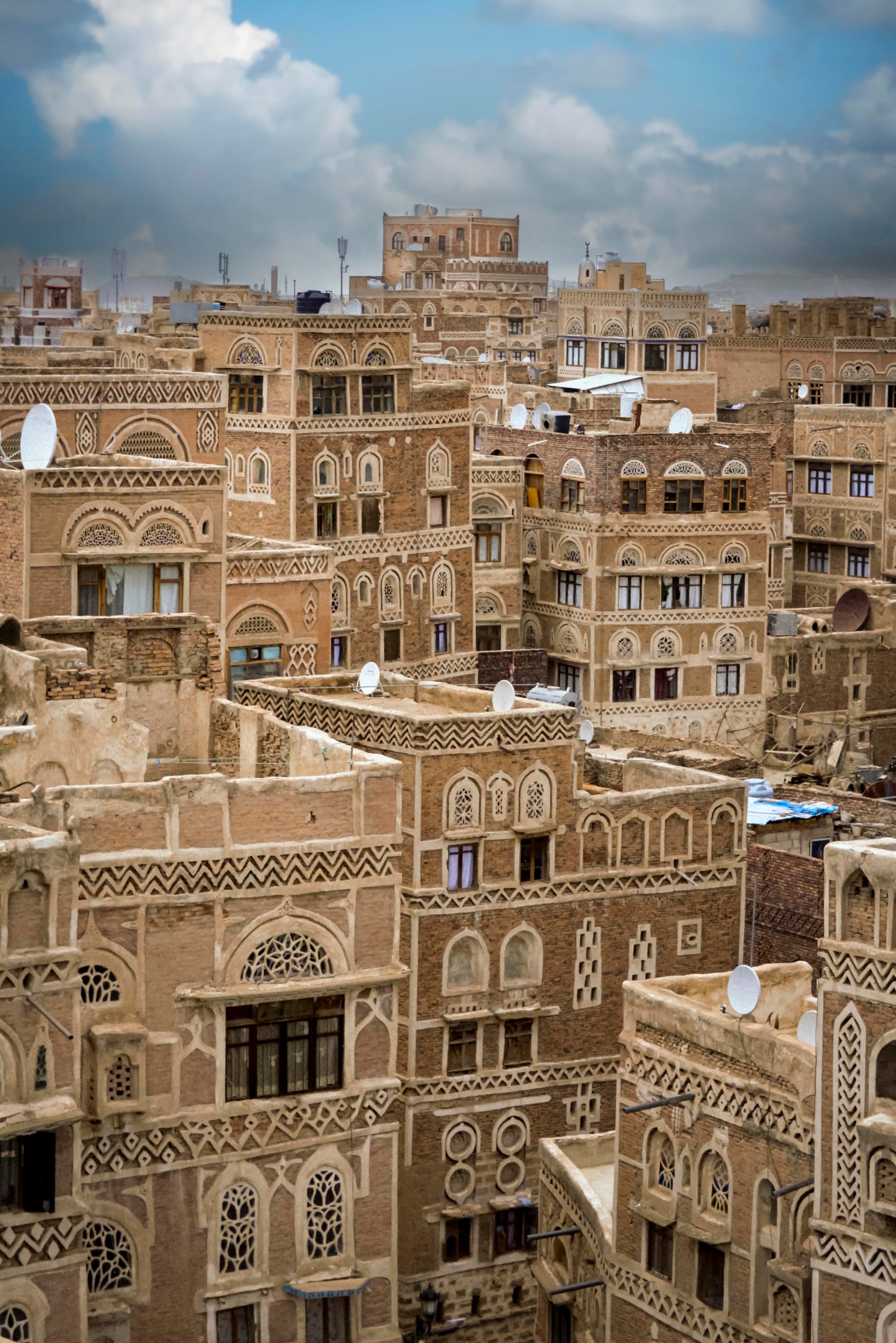 A dense old city of tall mud-brick and stone tower houses decorated with white gypsum patterns