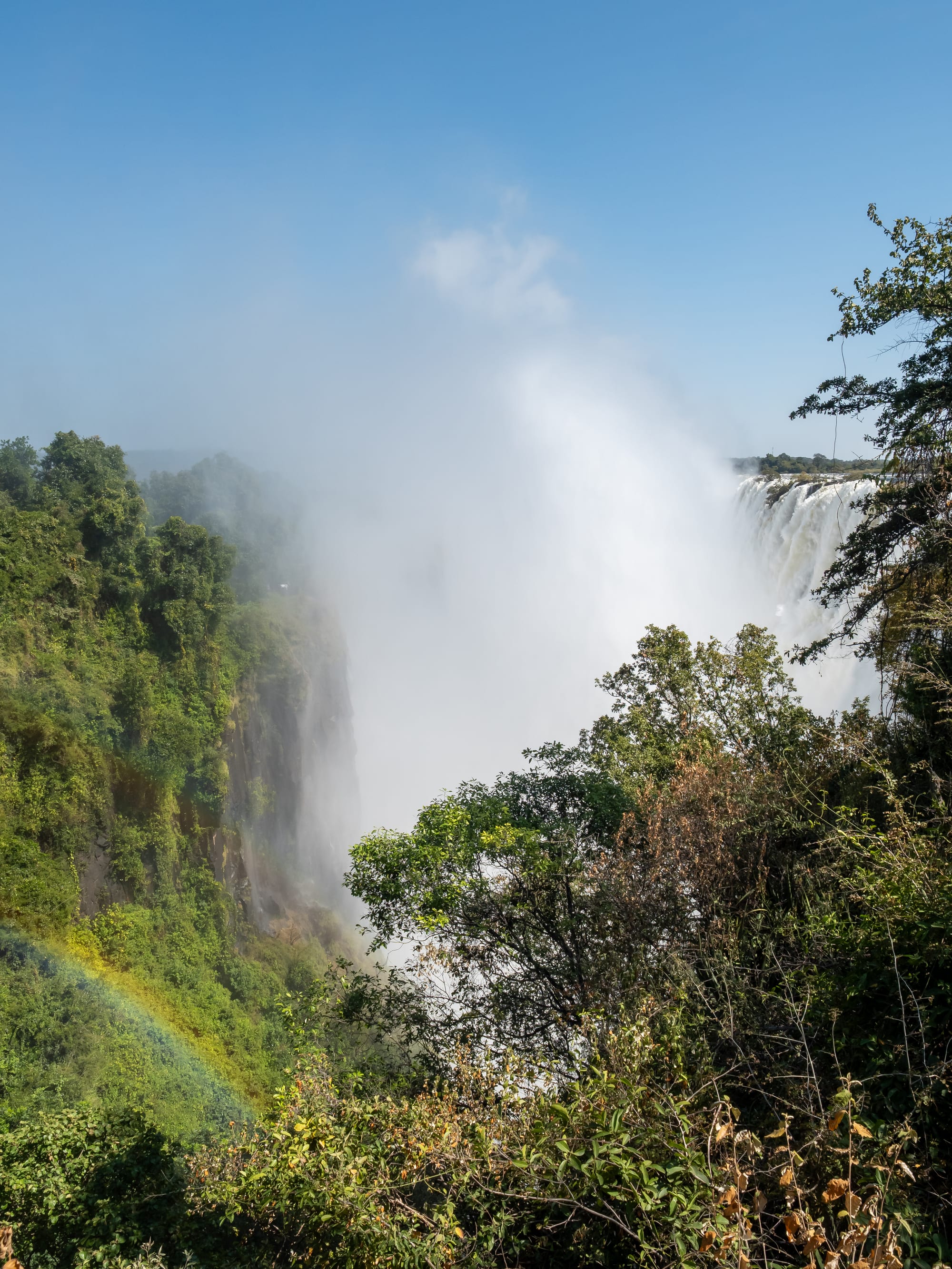 A vast curtain of water plunging into a mist-filled gorge at Victoria Falls, seen from the Zambian side