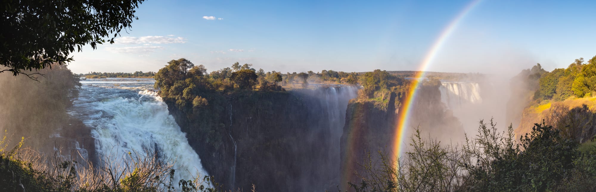 A vast waterfall spanning a wide gorge with heavy mist rising