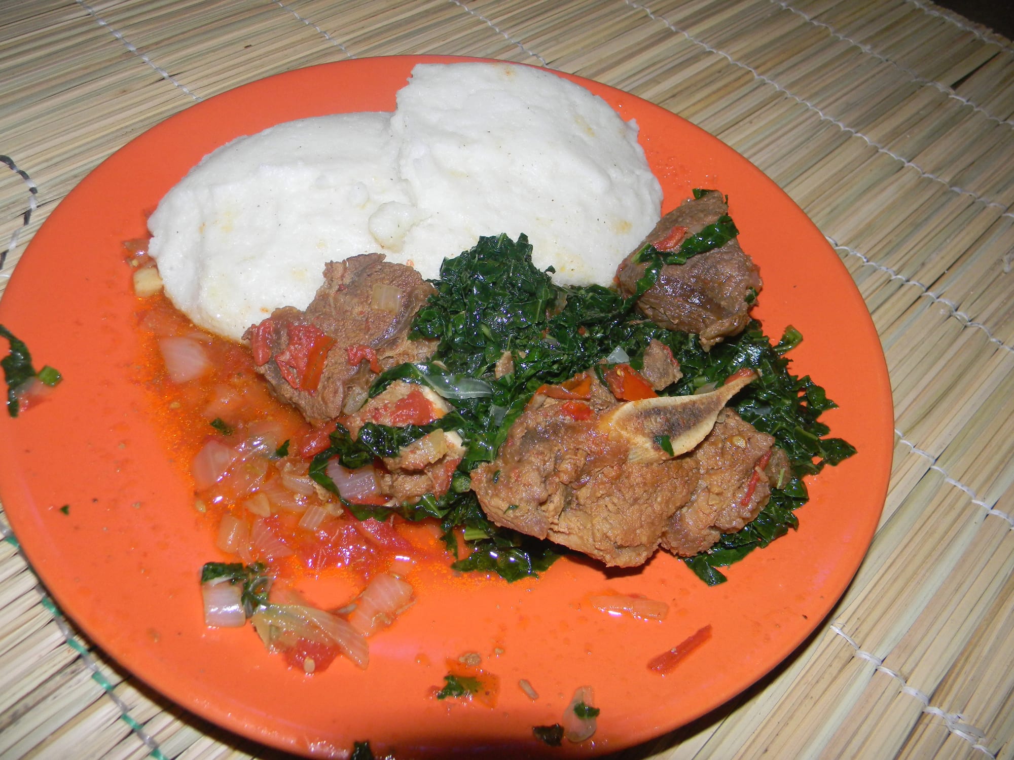 A plate of stiff maize porridge with meat and vegetables