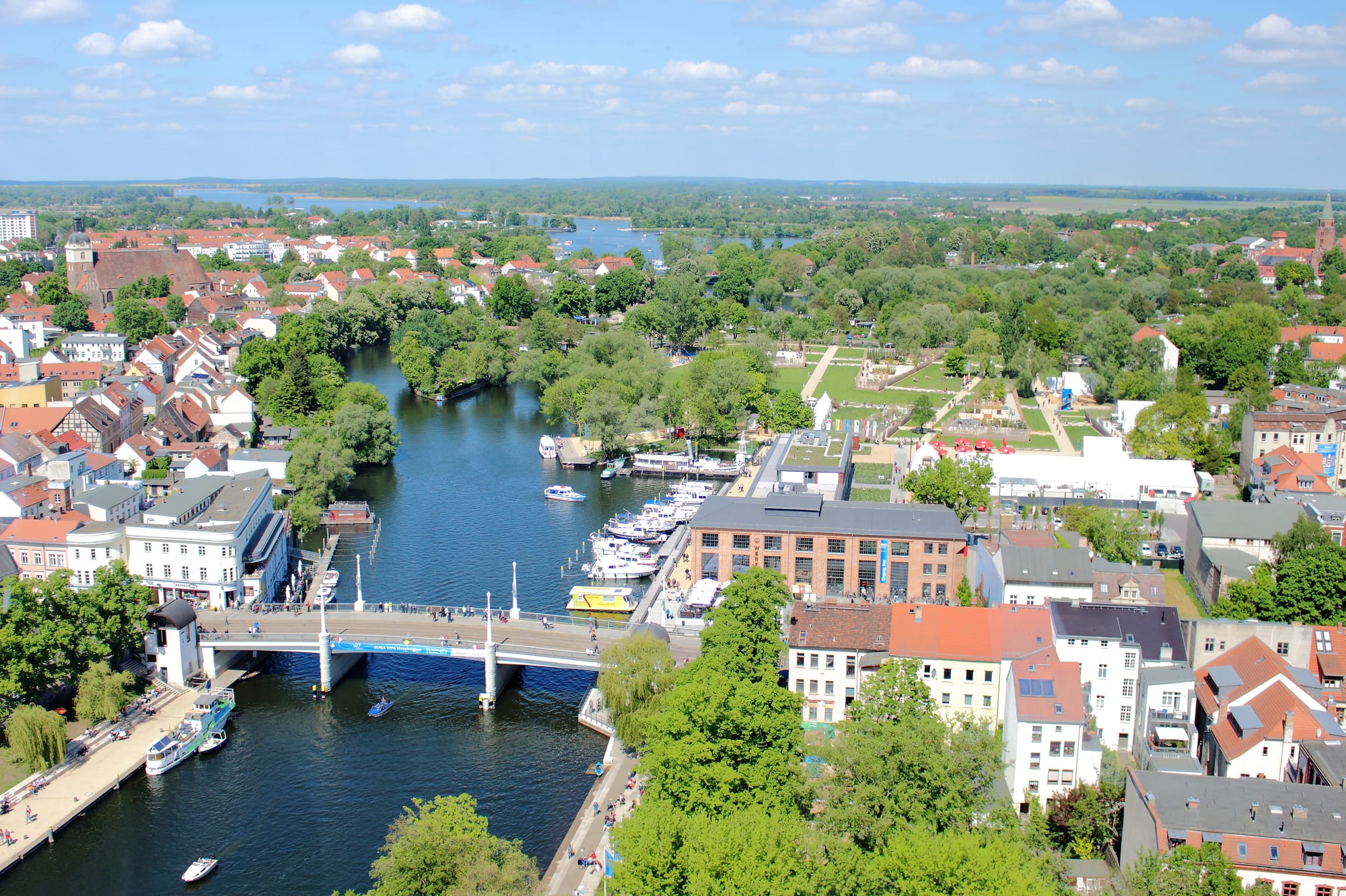 Aerial view of the Havel winding through Brandenburg an der Havel, with a bridge, moored boats, red roofs and lakes beyond