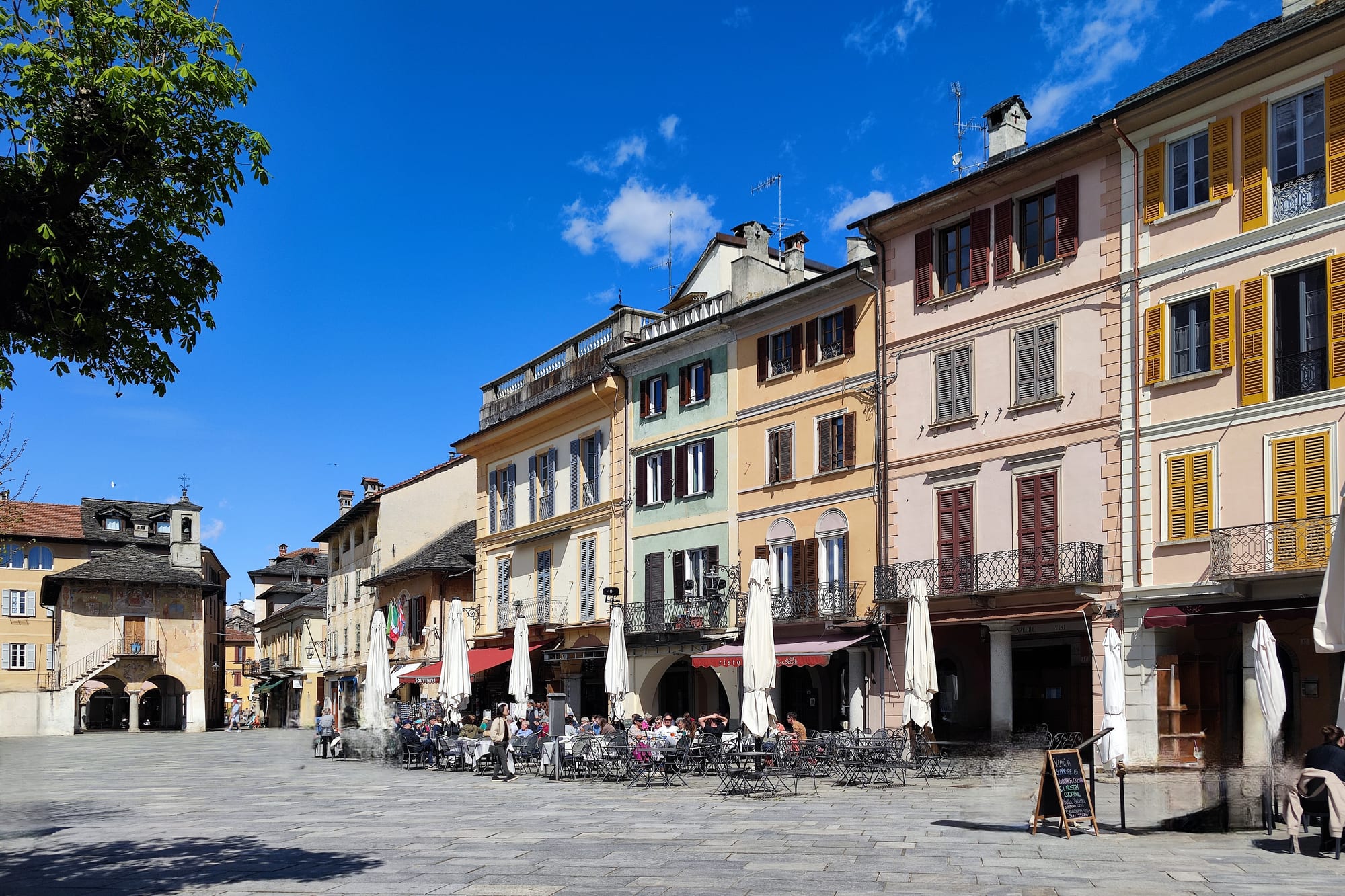 Pastel houses with shuttered windows and café tables in a paved square