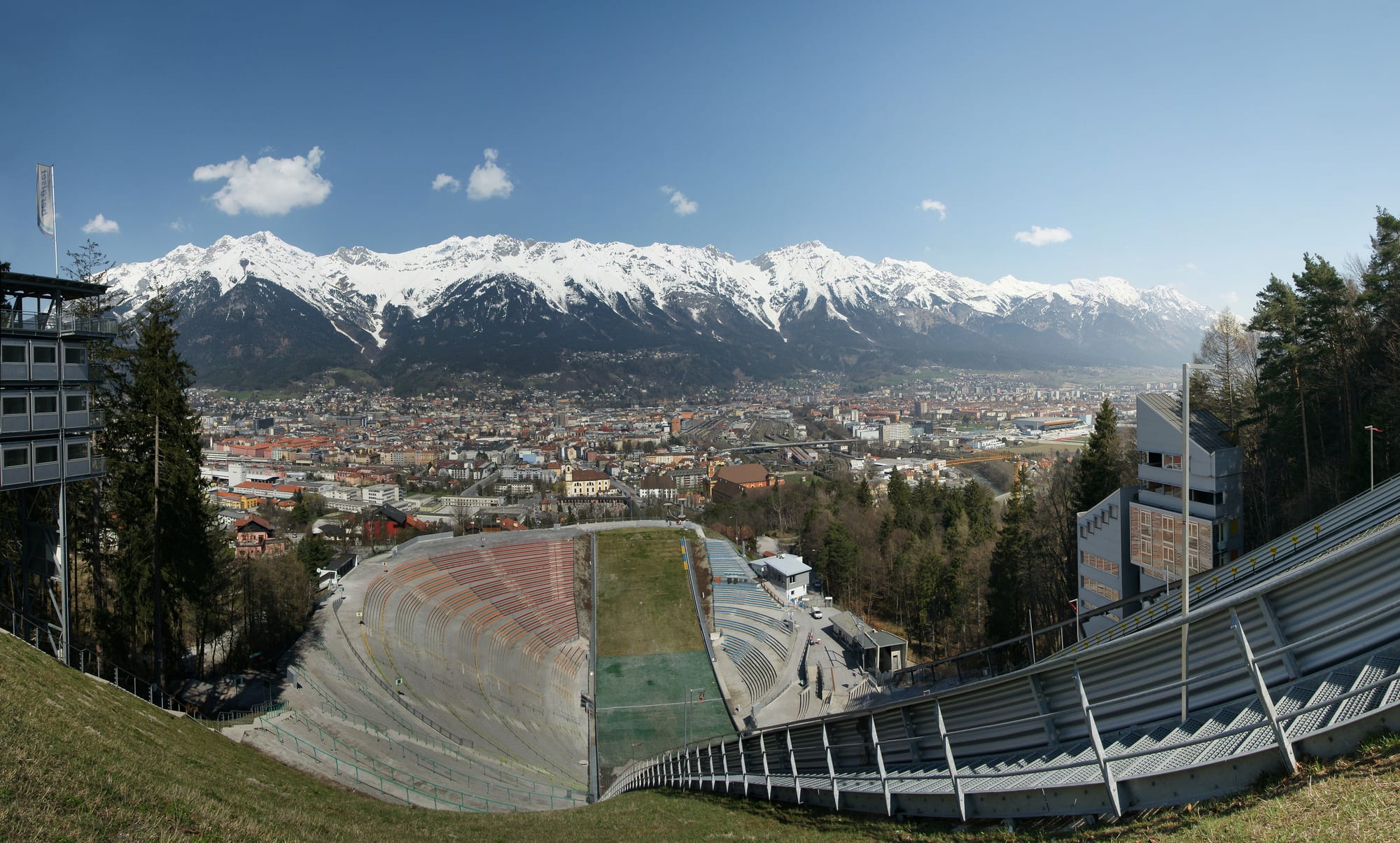 Innsbruck filling the Inn valley below the long snow-covered wall of the Nordkette, seen over a ski-jump arena