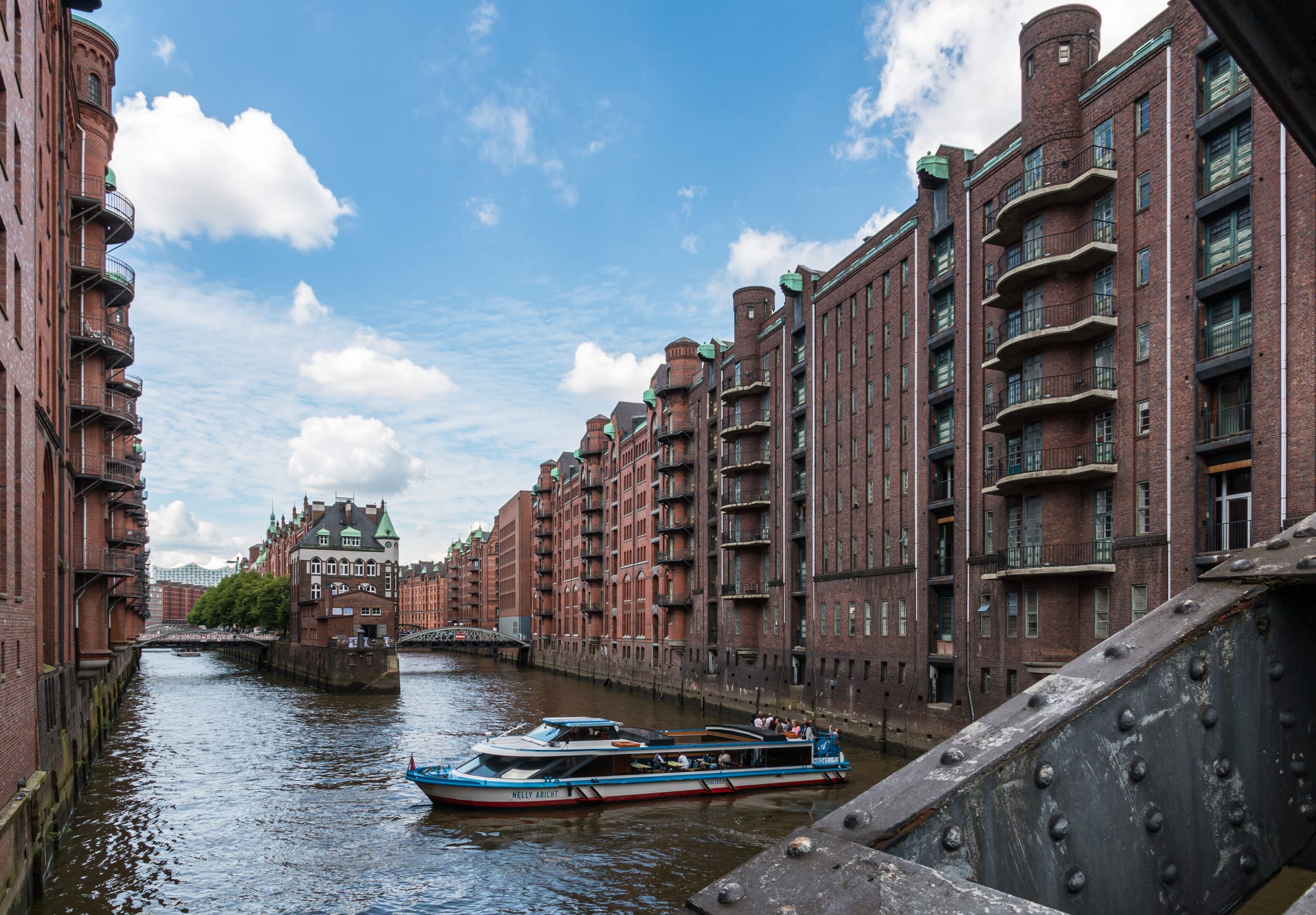 The red-brick Wasserschloss at the fork of two canals in Hamburg's Speicherstadt, with a boat on the water
