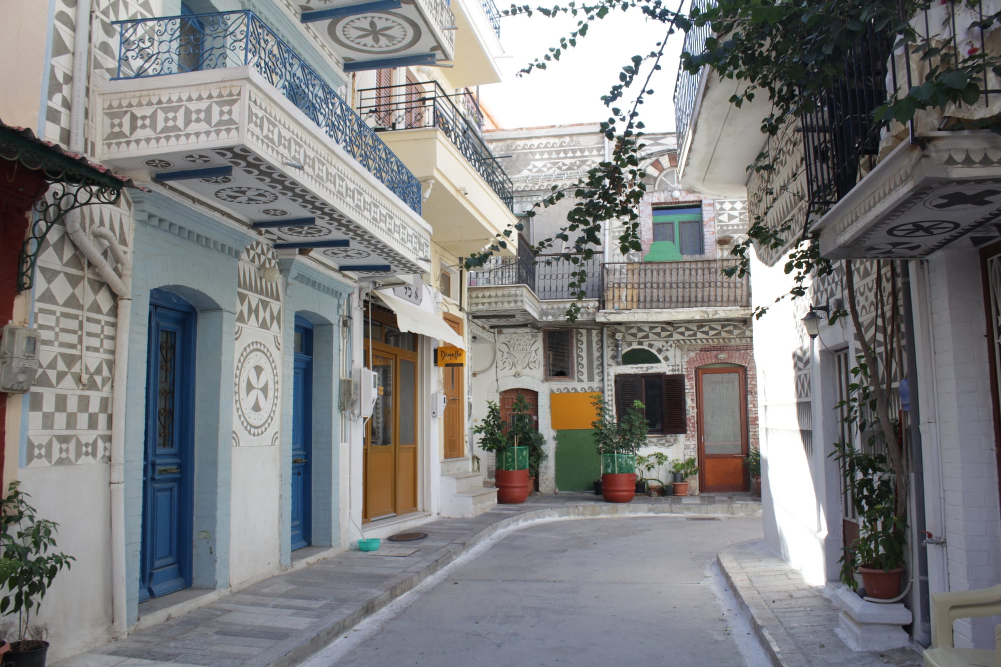 A narrow village street lined with houses whose walls are covered in grey-and-white geometric patterns