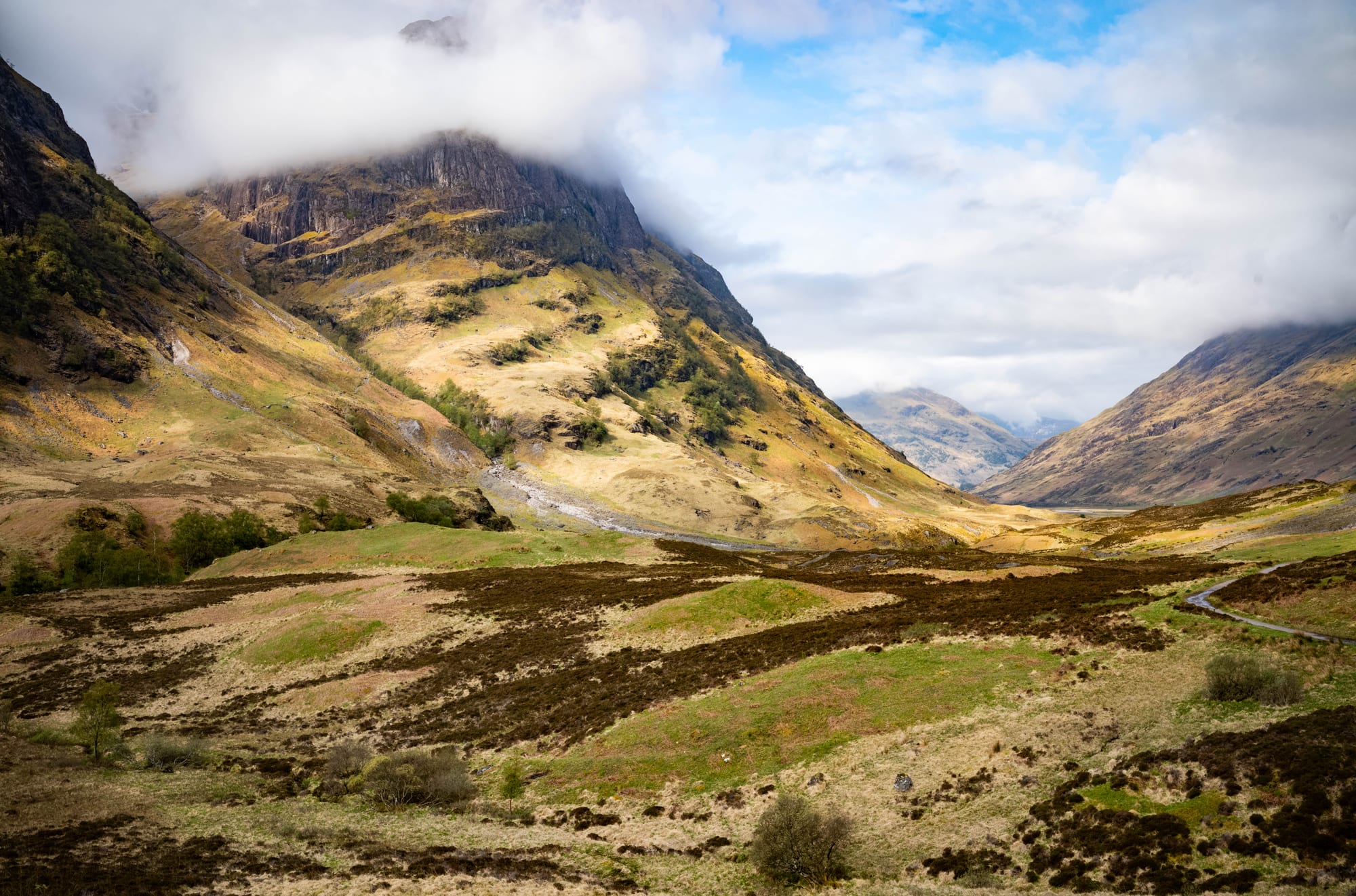 A wide glen of heather and grass between steep mountain slopes, the highest summit hidden in low cloud