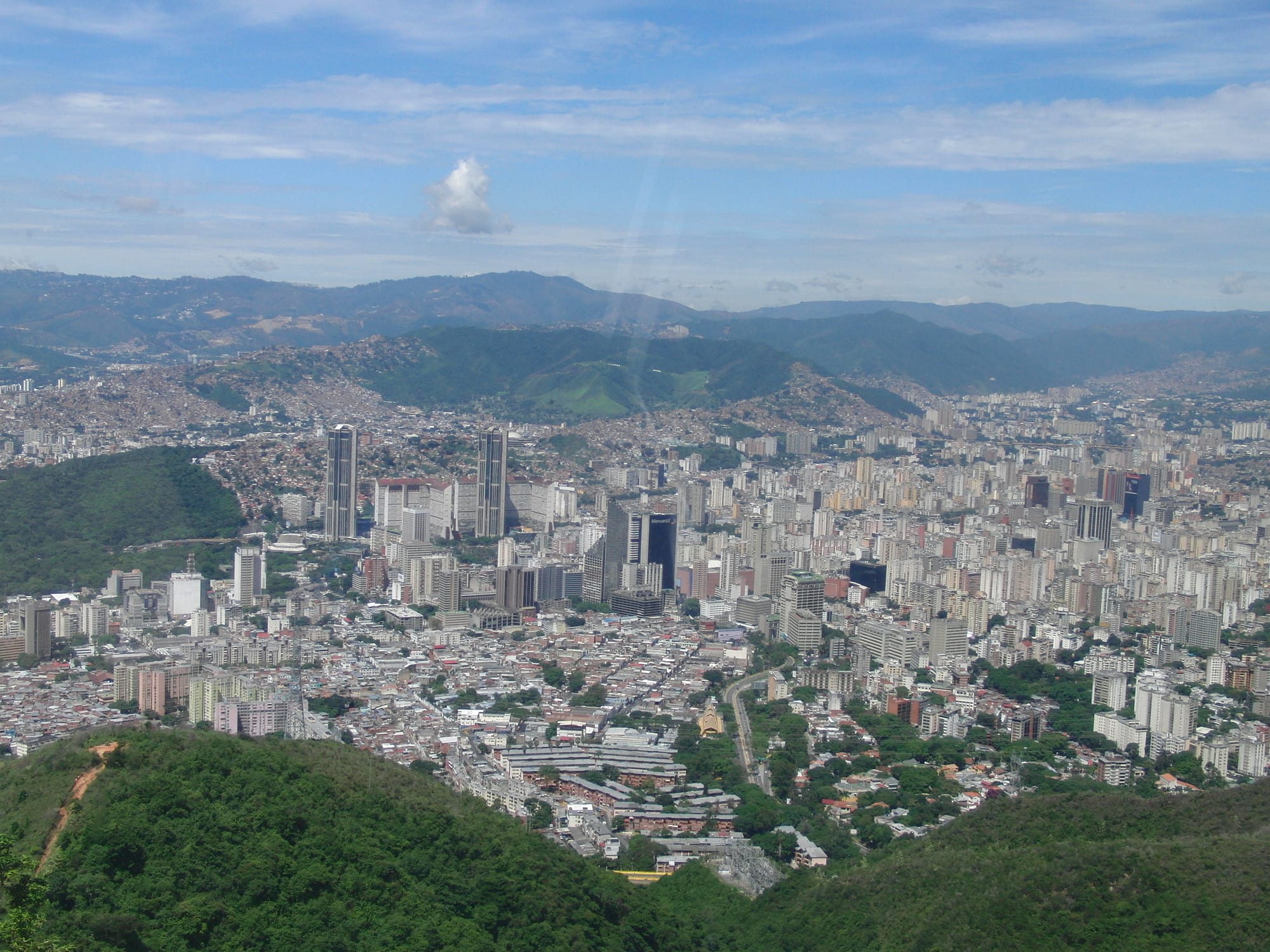 Caracas seen from the forested slopes of the Ávila, with the twin Parque Central towers and hillside barrios beyond